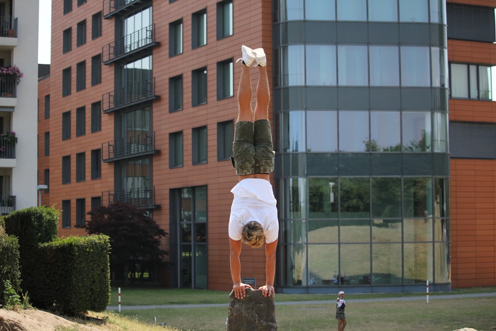 man squatting on rock near building