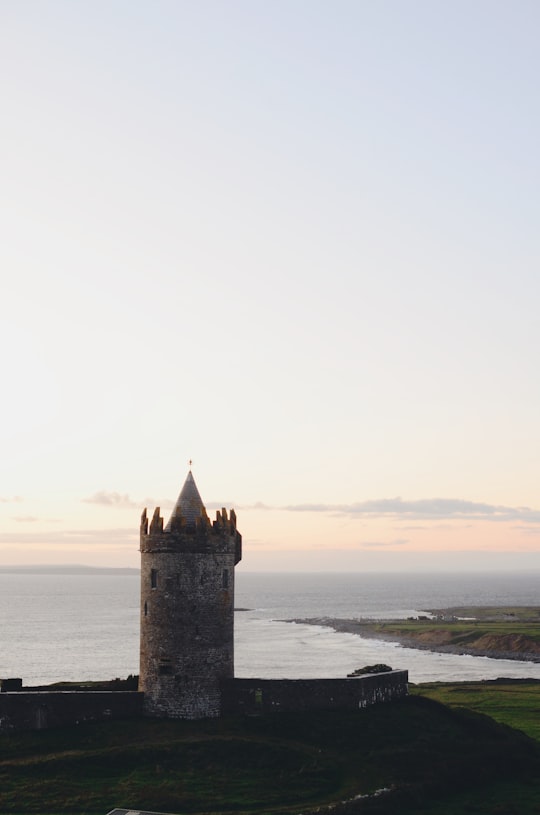 brown castle beside ocean in Doolin Ireland