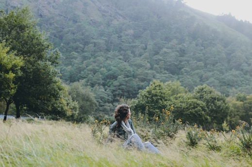 A calm, serene scene of a person sitting peacefully in nature, reflecting quietly.