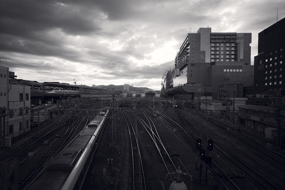 train on rail way between buildings in grayscale photo