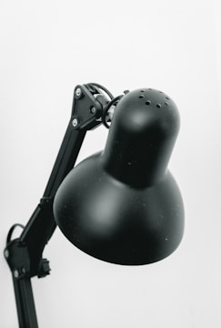 A close-up of a stylish desk lamp on a workspace.