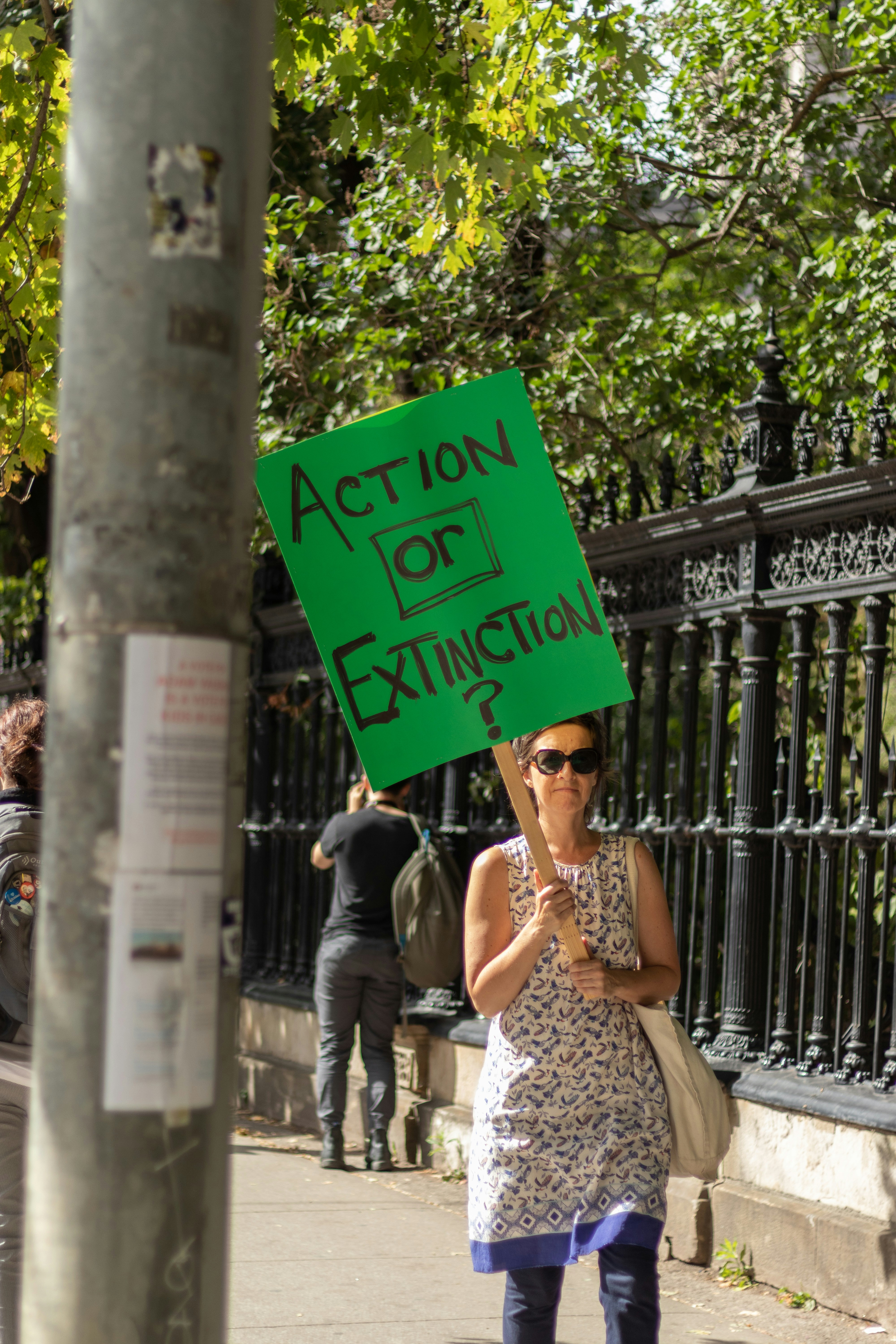 femme marchant sur le trottoir tenant un panneau d’action verte ou d’extinction
