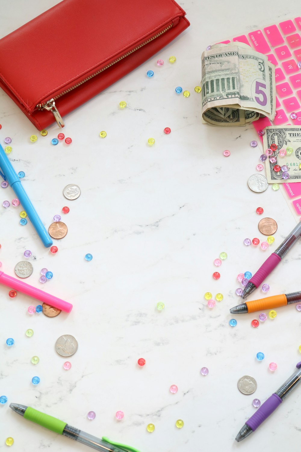 assorted color pens near dollar bills and zip wallet