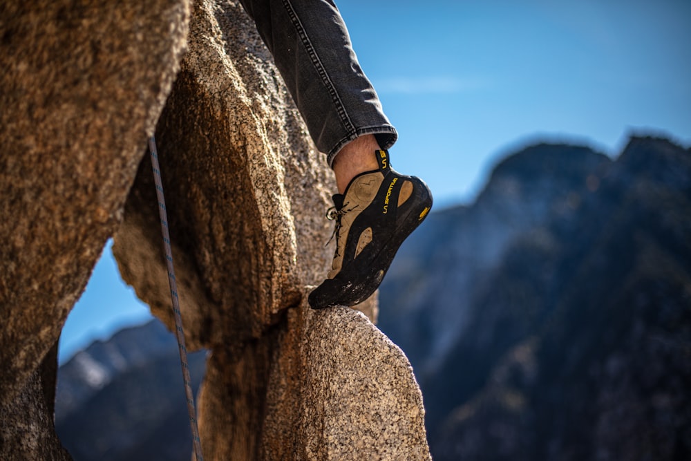 man climbing the rock formation during daytime