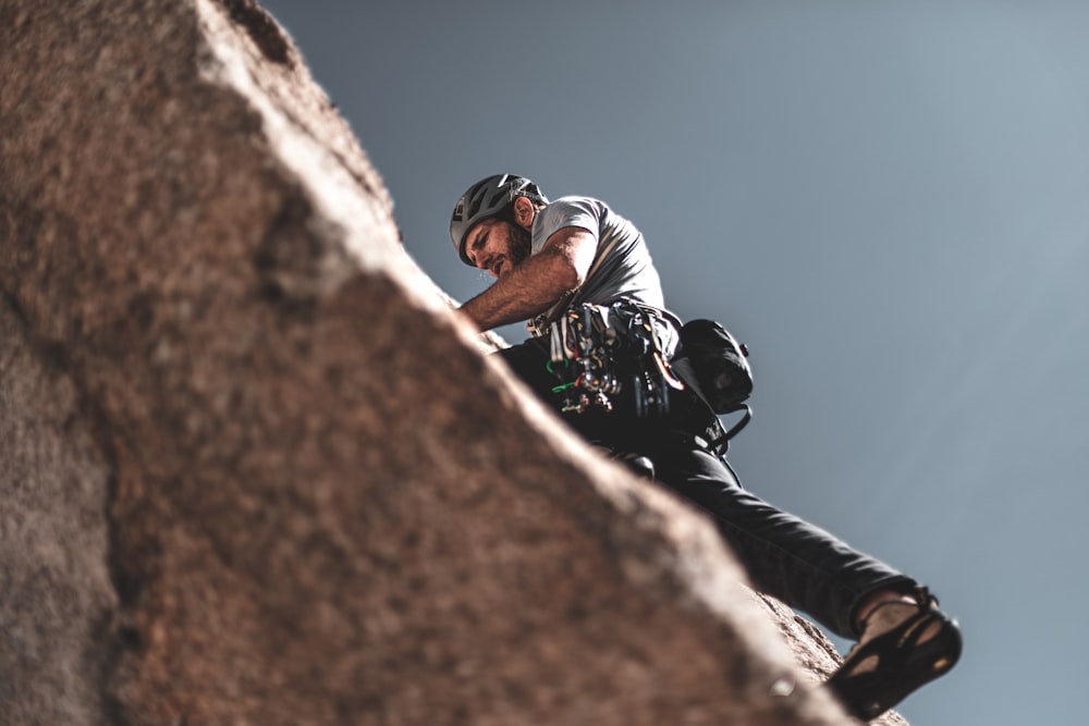 man climbing on gray rock