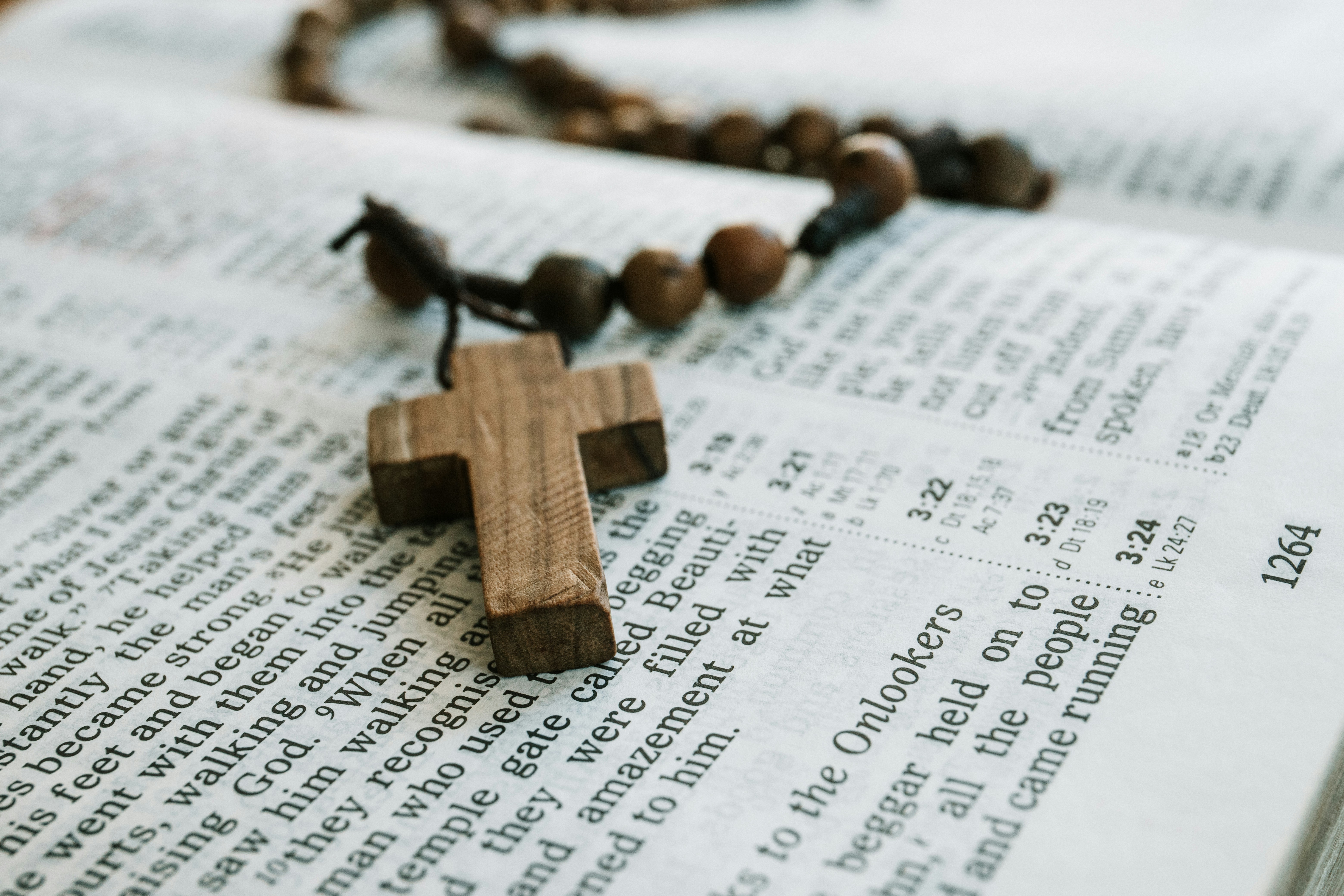 A wooden rosary rests on the pages of an open book.