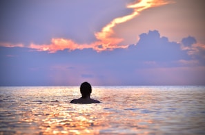 man swimming at a beach at sunset