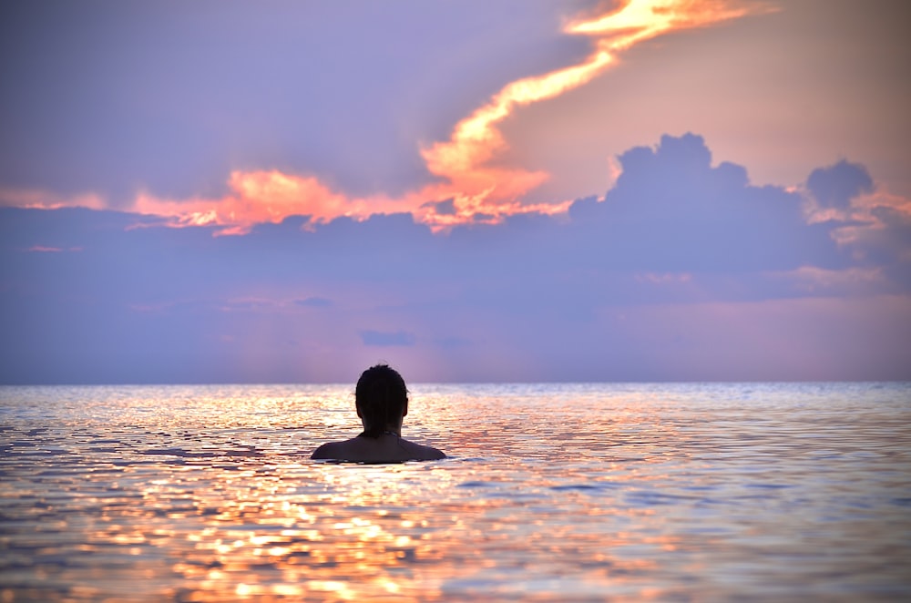man swimming at a beach at sunset