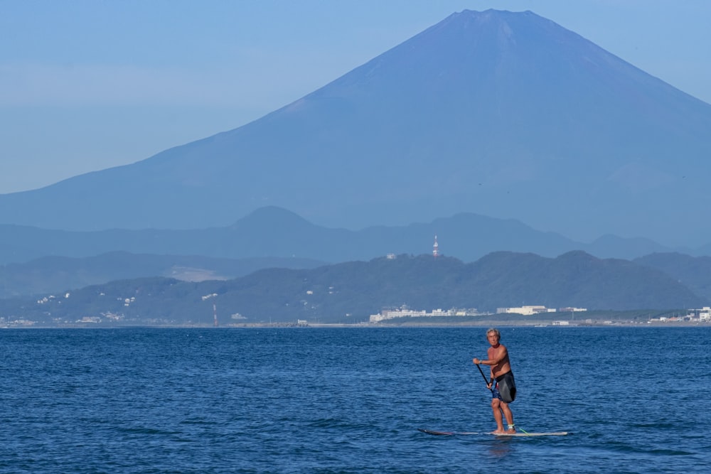Mann mit Surfbrett und Berg im Hintergrund