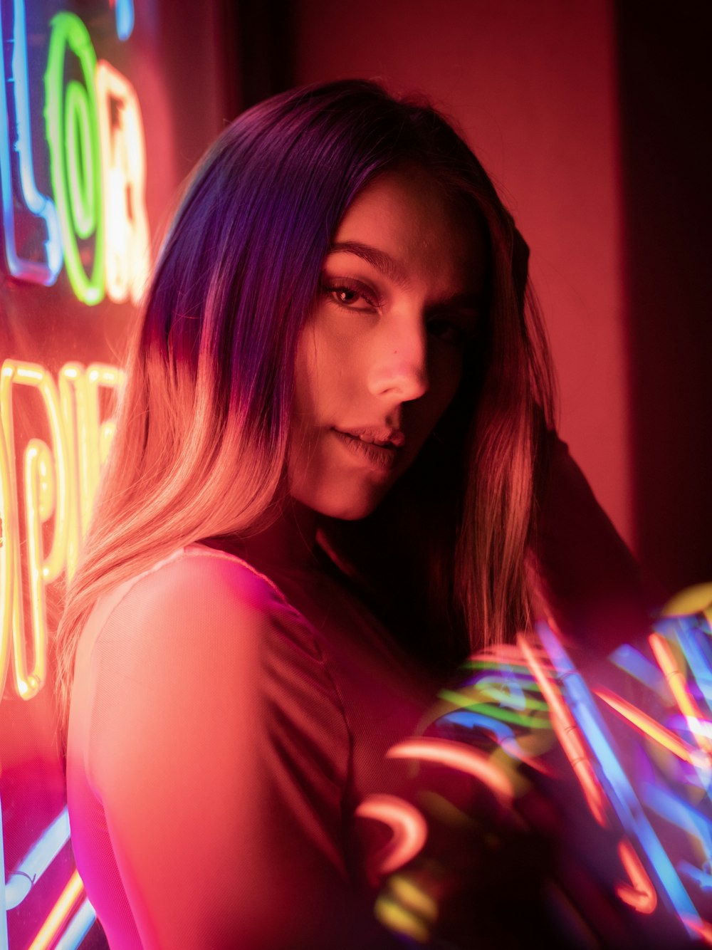 woman wearing white top behind of assorted-colored LED lights looking at side