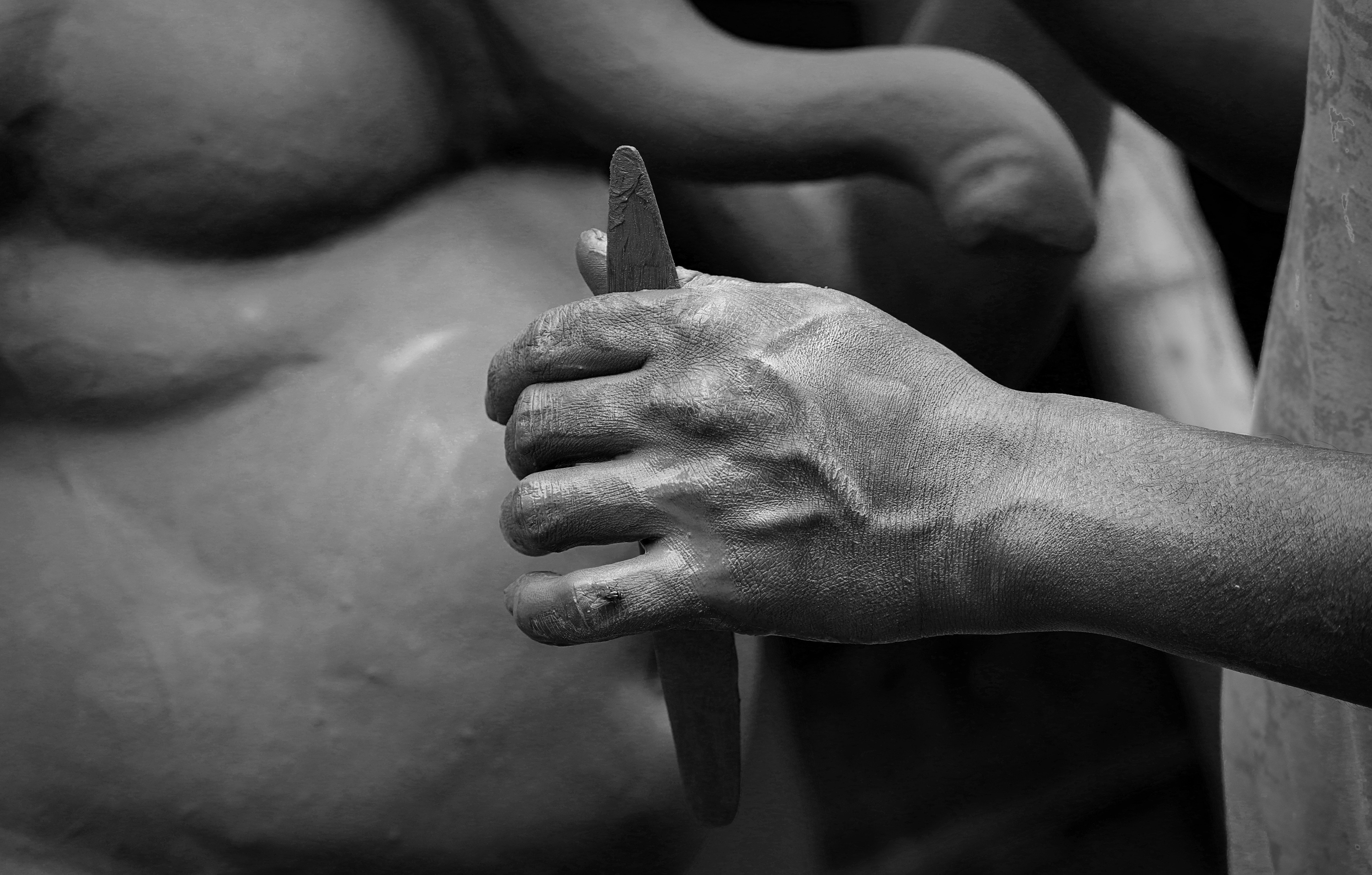 person holds sculpture tool in front elephant statue
