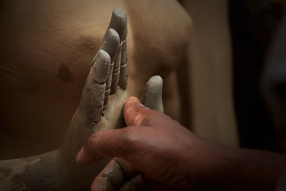 person holding gray hand statue