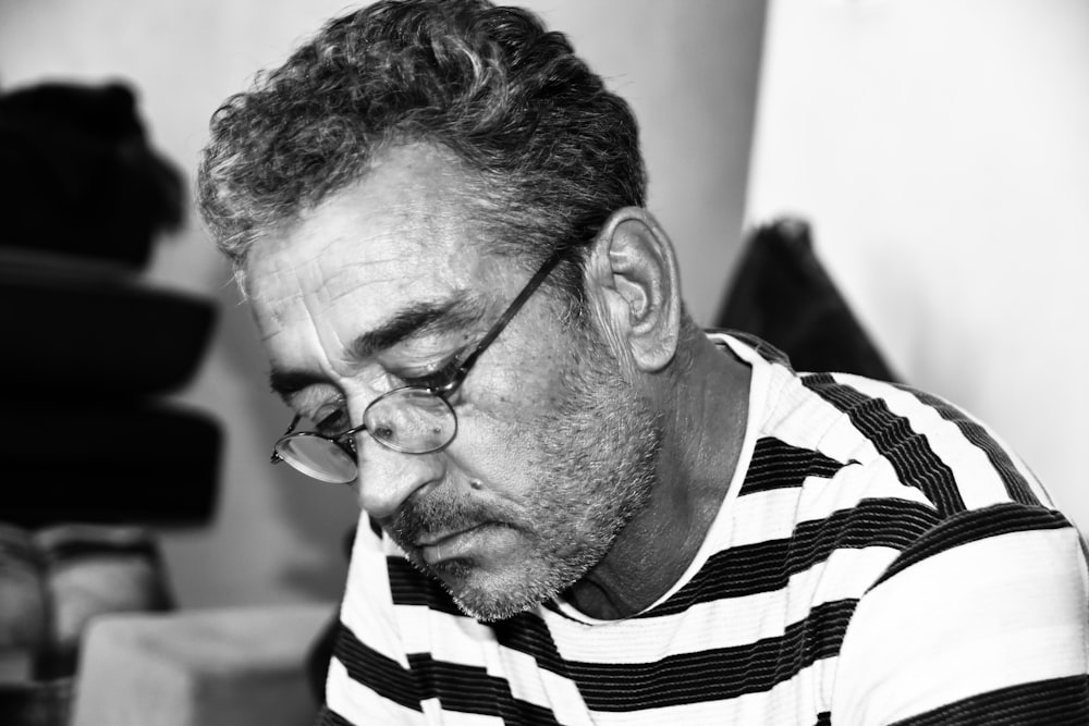 grayscale photography of man wearing eyeglasses and striped shirt
