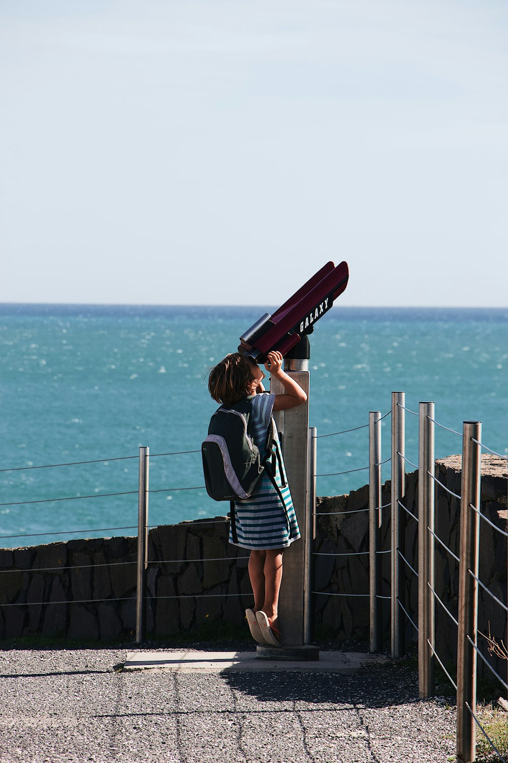 girl carrying backpack using telescope