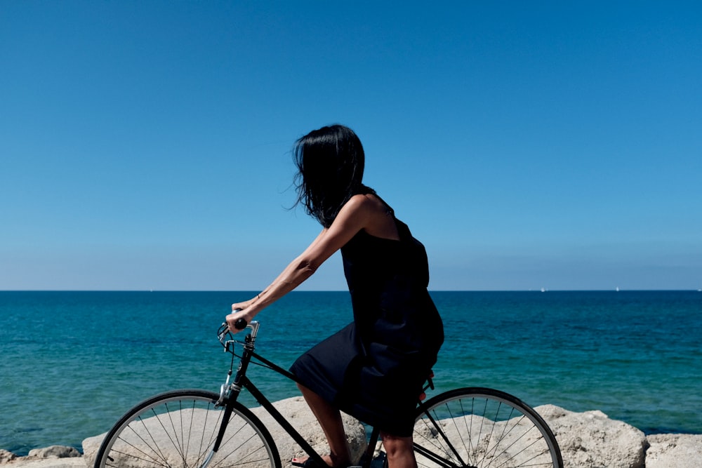 woman riding bicycle near body of water