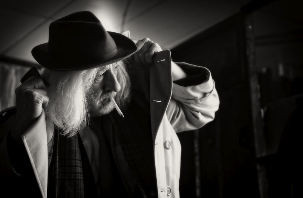 grayscale photography of man wearing hat and coat