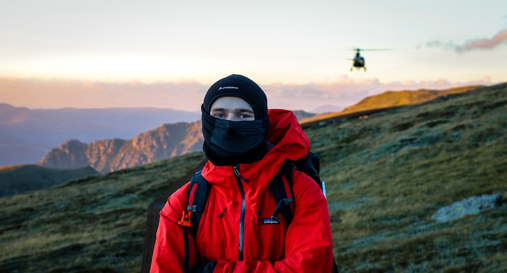 homme portant une veste zippée rouge et noire pendant la journée