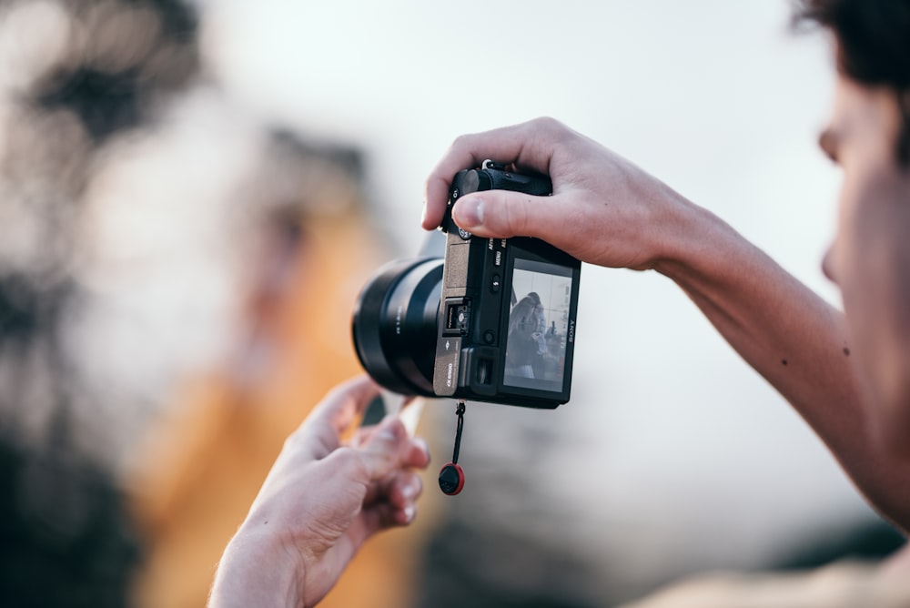 person holding black DSLR camera