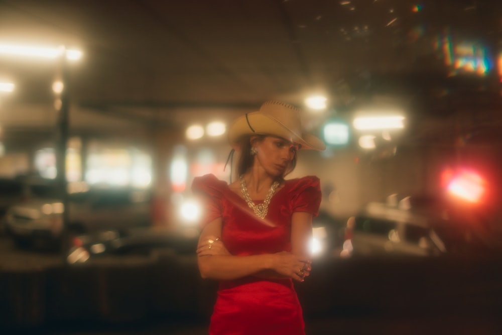 La femme porte une robe rouge et un chapeau de cow-boy marron