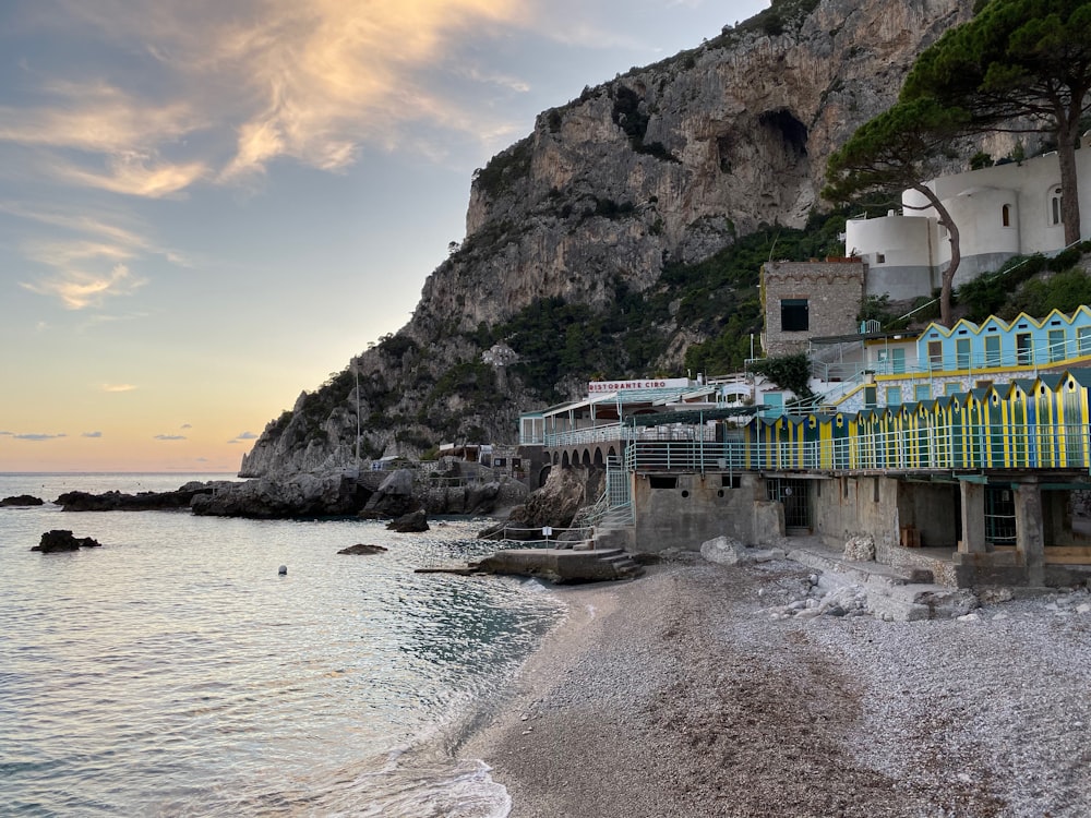 white and green house near seashore viewing cliff under blue and white sky during daytime