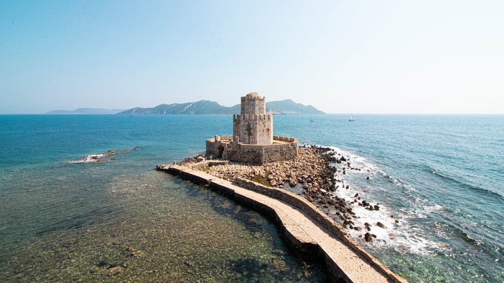 castle on isle with bridge during day