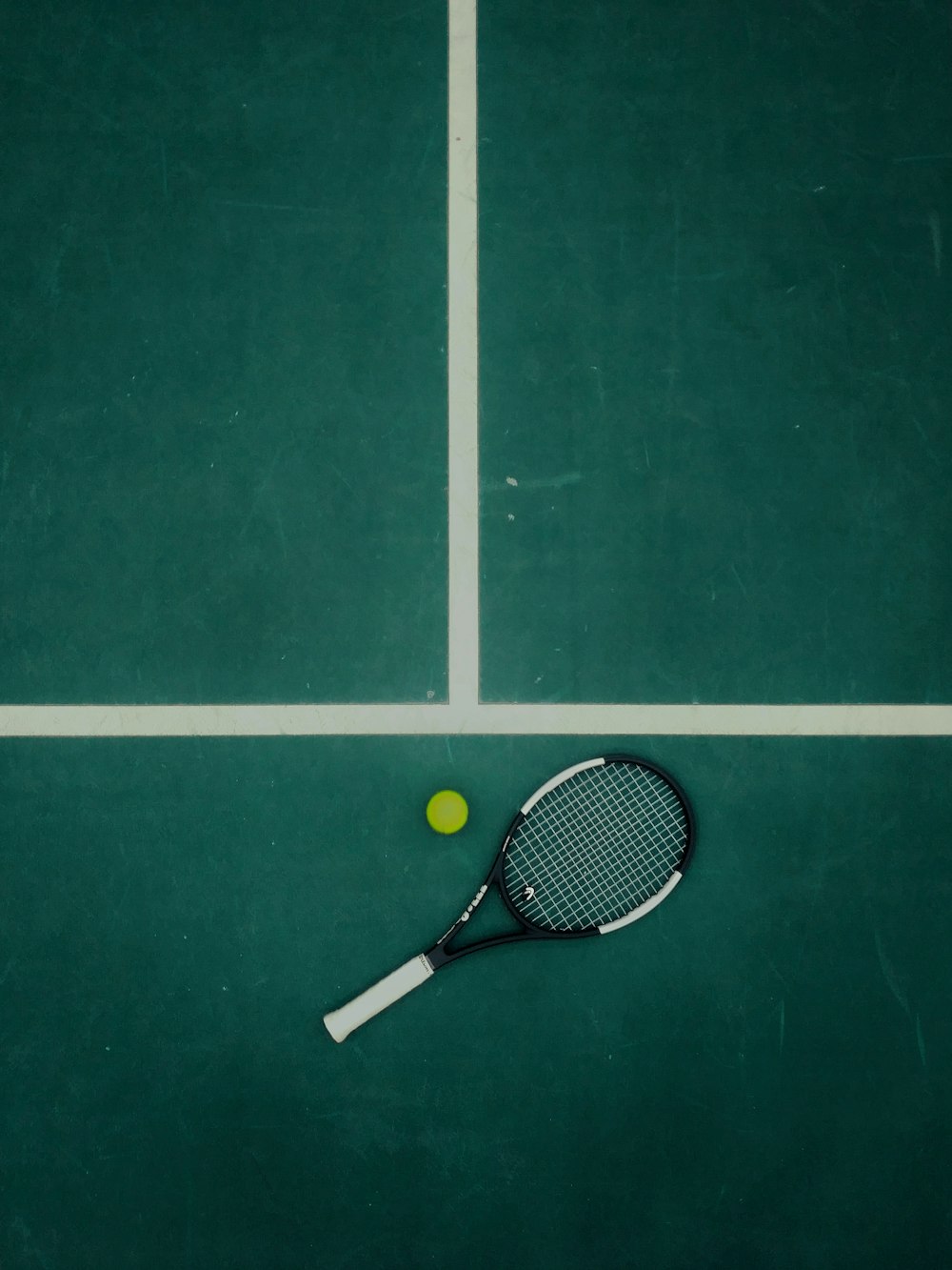 black and white tennis racket beside ball