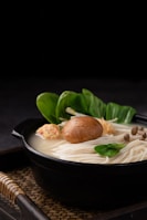 Rich presentation of the Gombo Royal in a stylish black bowl with golden garnish.