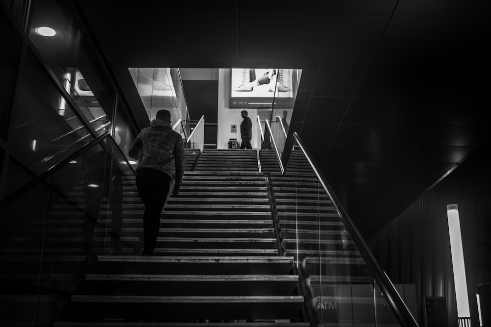 콘크리트 계단을 걷는 남자의 회색조 사진