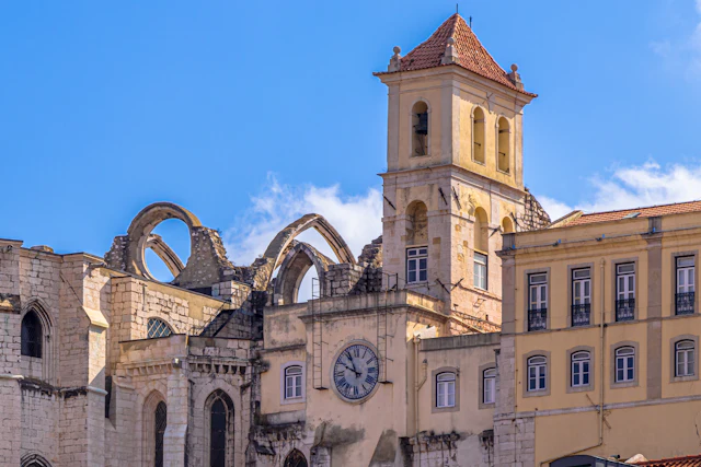 The ruined Gothic arches and bell tower of the Carmo Convent in Chiado against a blue sky