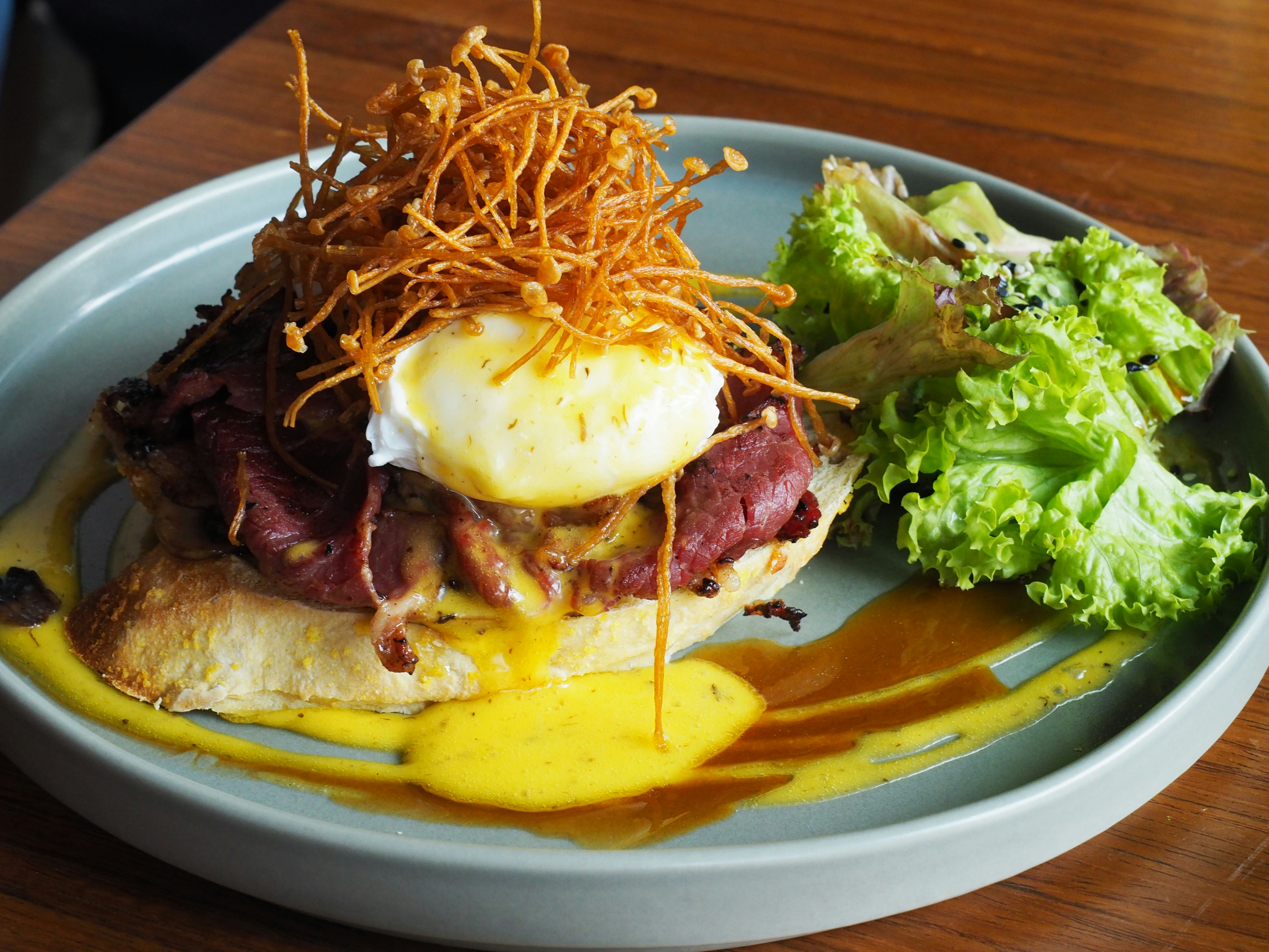 Eggs benedict topped with crispy shoestring potatoes and salad