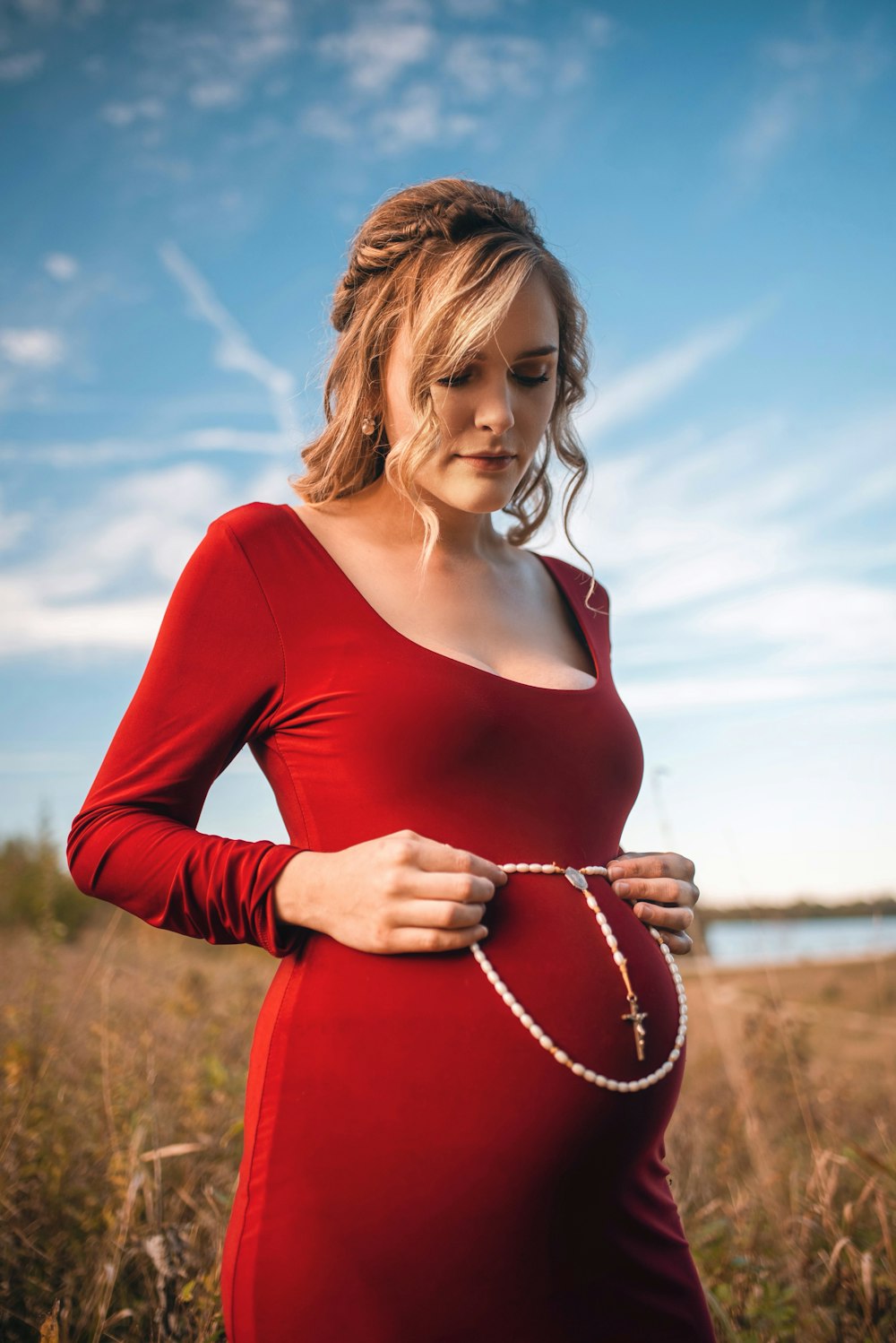 pregnant woman wearing red dress holding white rosary