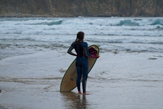 woman holds white surfboard near ocean