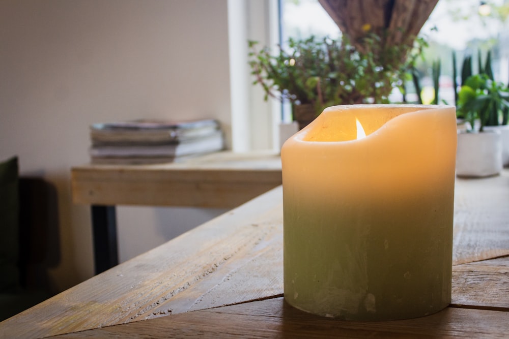 lighted white pillar candle on table