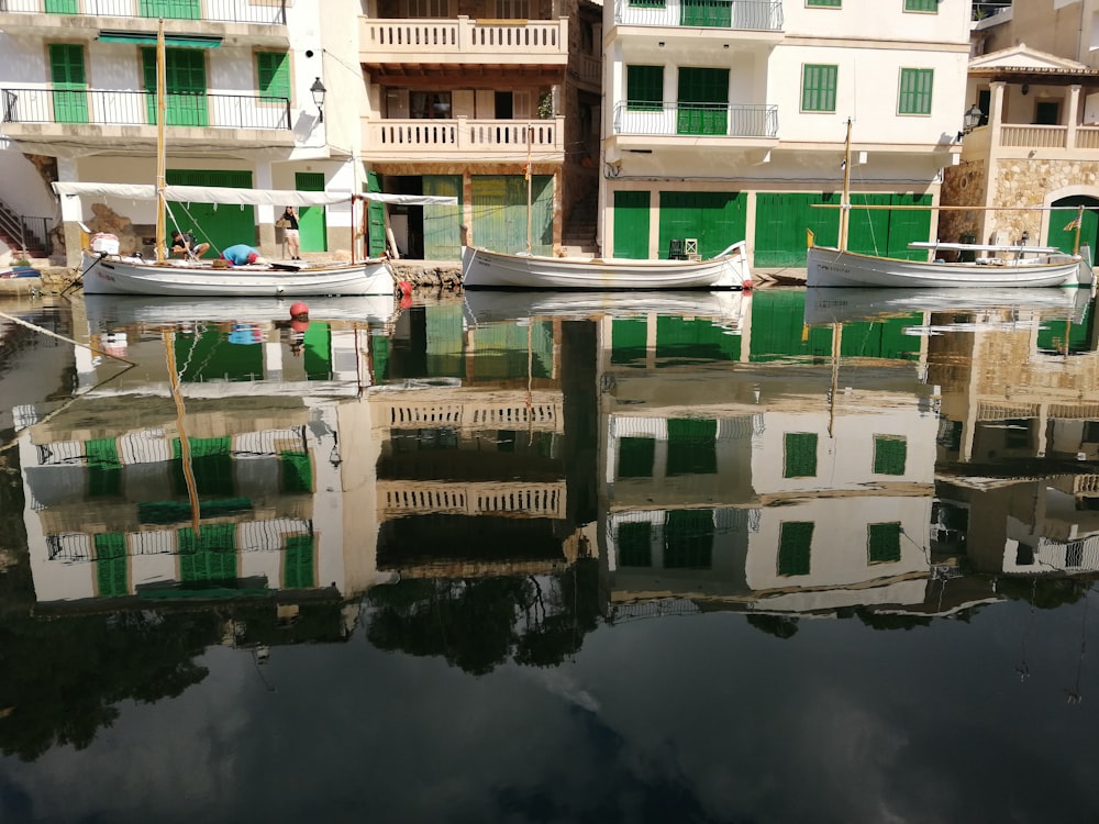 white boats on body of water beside buildings