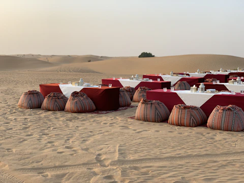 Romantic desert dinner setup under a starry sky with golden lanterns