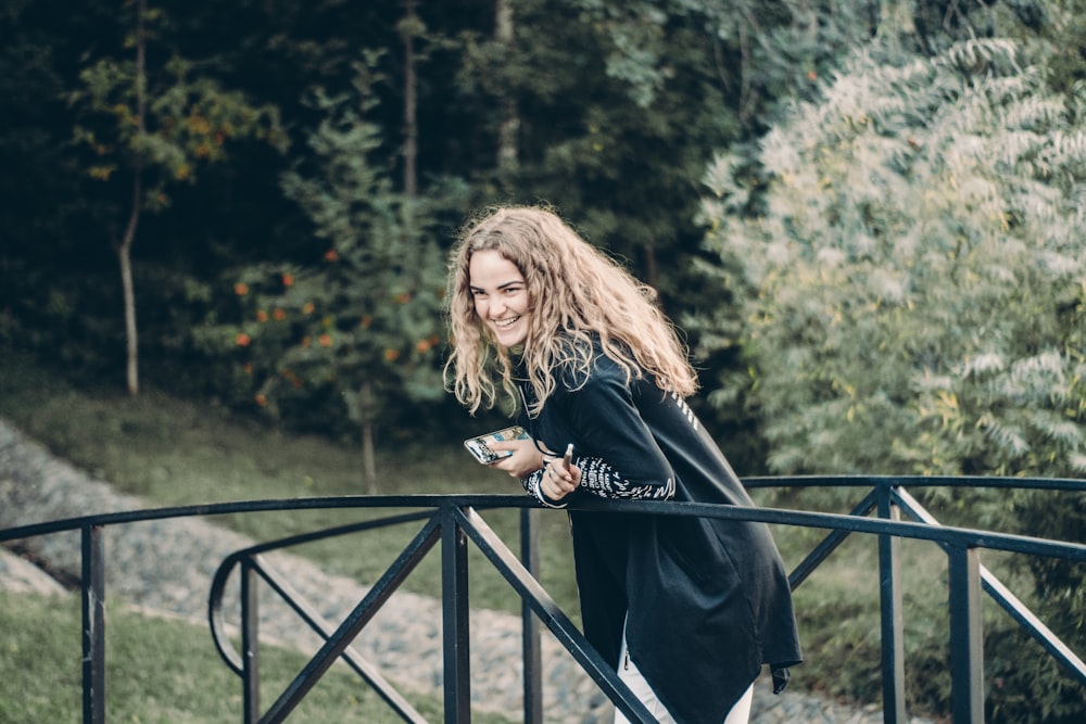 smiling woman leaning on black metal rail during daytime