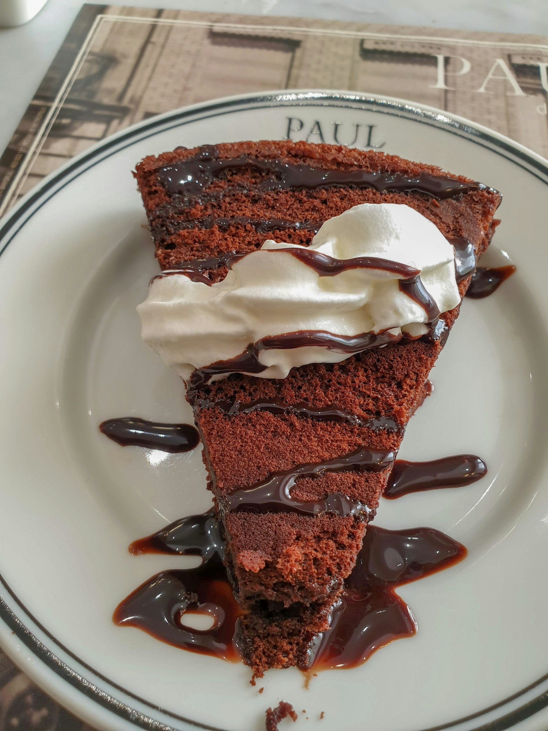Decadent slice of chocolate cake with rich frosting and a drizzle of chocolate syrup, ready to enjoy at Cafe Villa.