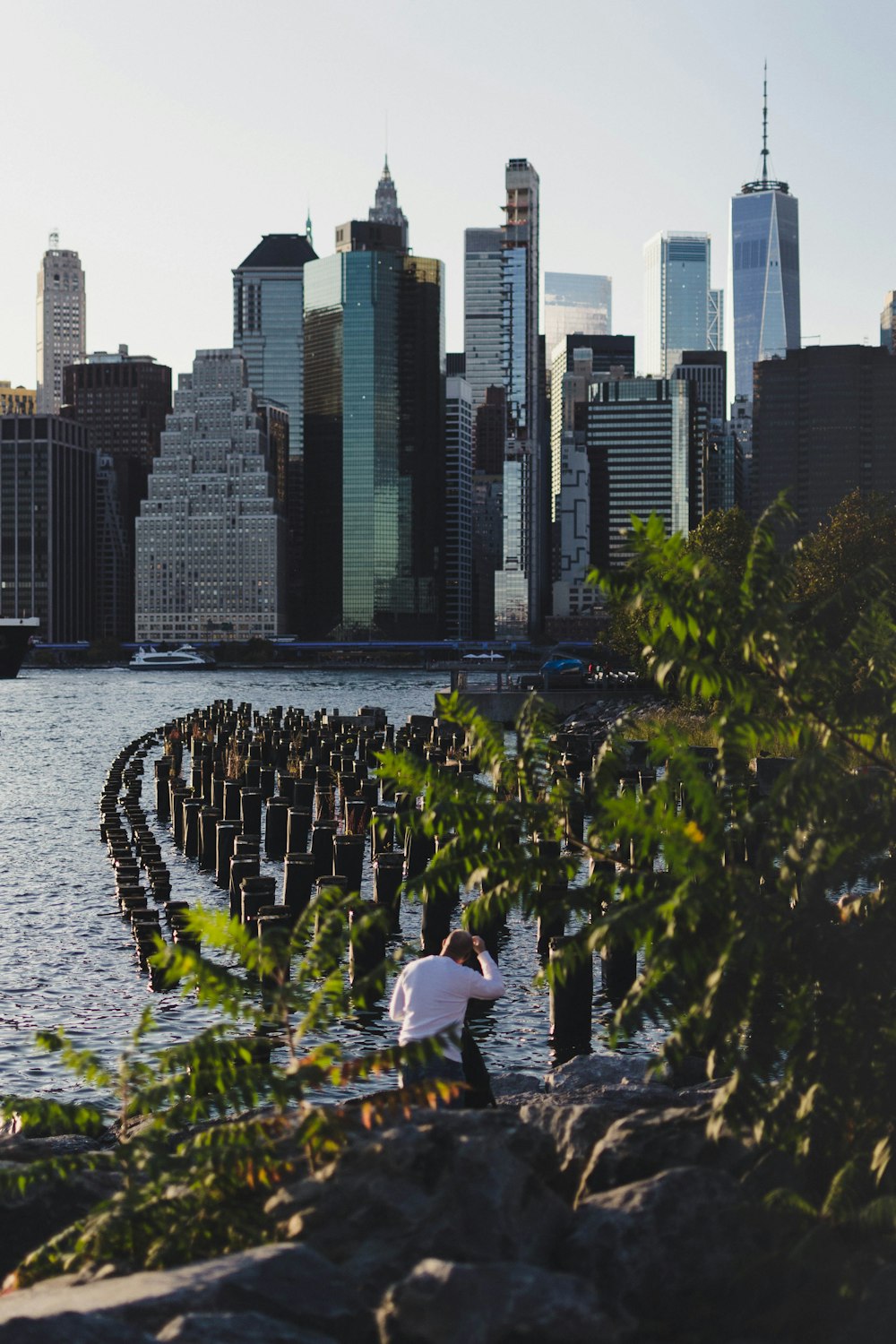 man sitting on rock fronting body of water in the city