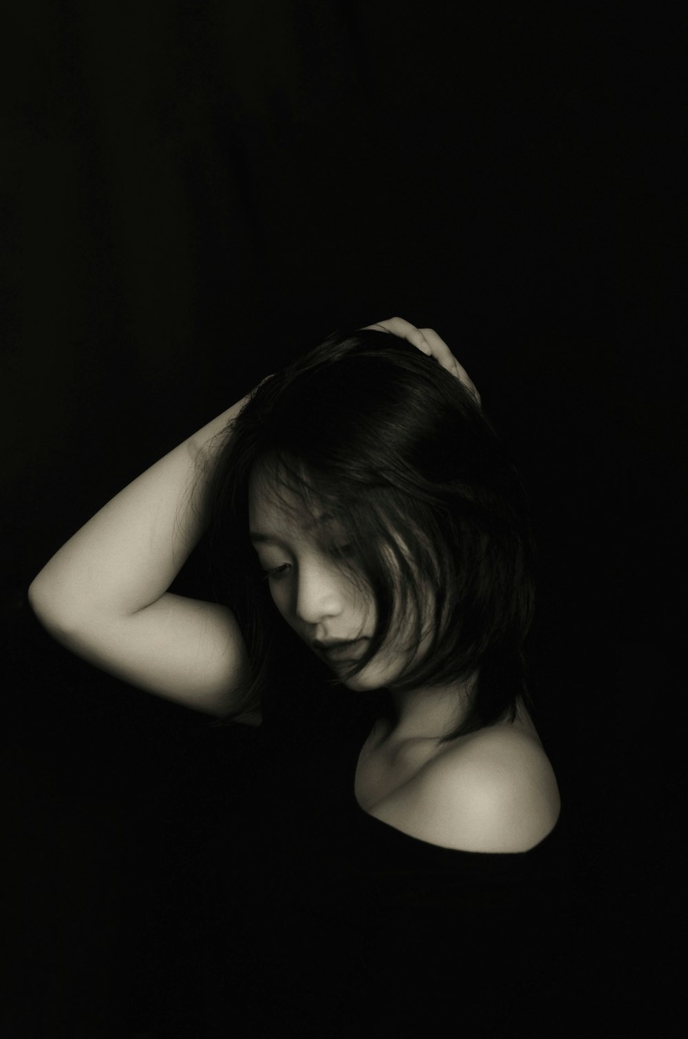 grayscale photography of woman wearing shirt touching her hair