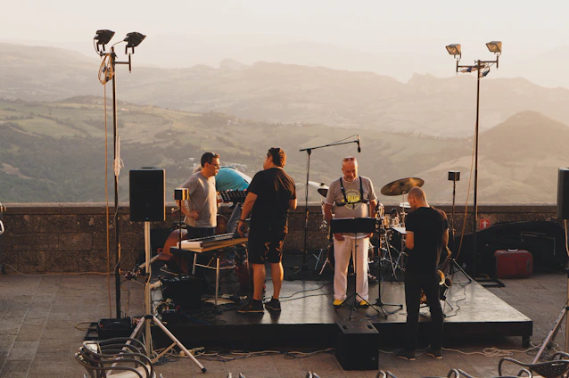 Photo of Bluegrass Pulse band members playing instruments on a rustic outdoor stage at sunset.