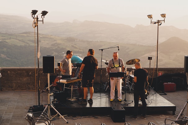 The four members of Trouble Creek playing instruments together on a rustic outdoor stage at sunset.