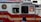 A red and white emergency vehicle with the FDNY HazMat logo and 'Specialists' written on its side. A person is visible inside the vehicle, and there is a pedestrian in the foreground.