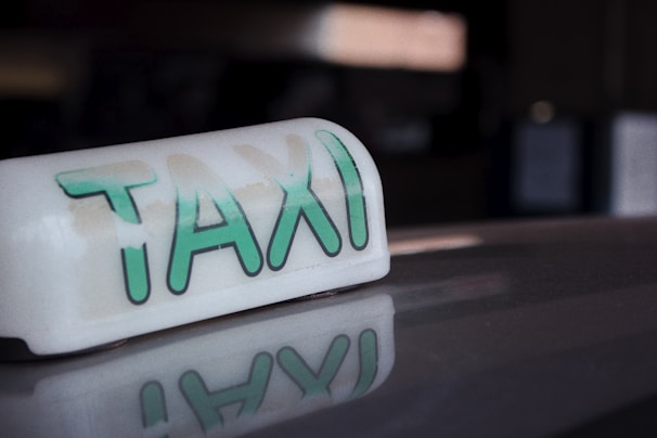 Close-up of a verified driver badge and a clean, shiny taxi emblem reflecting the city lights.