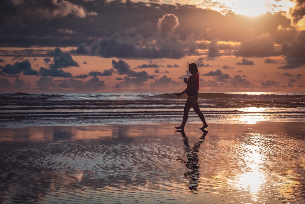 silhouette of person standing beside seashore