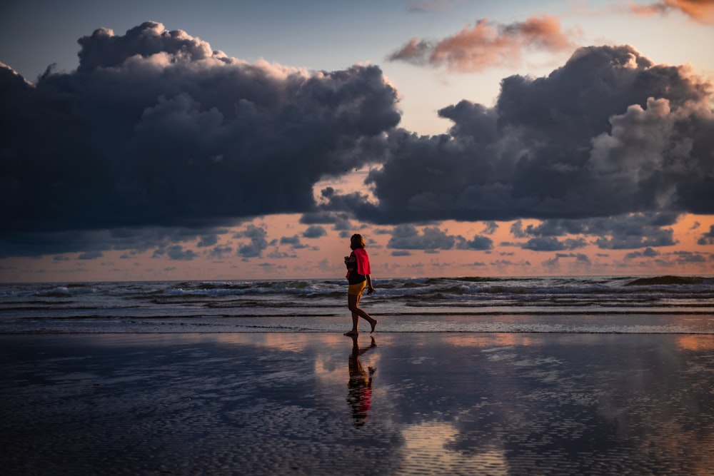 person walking beside seashore during daytime