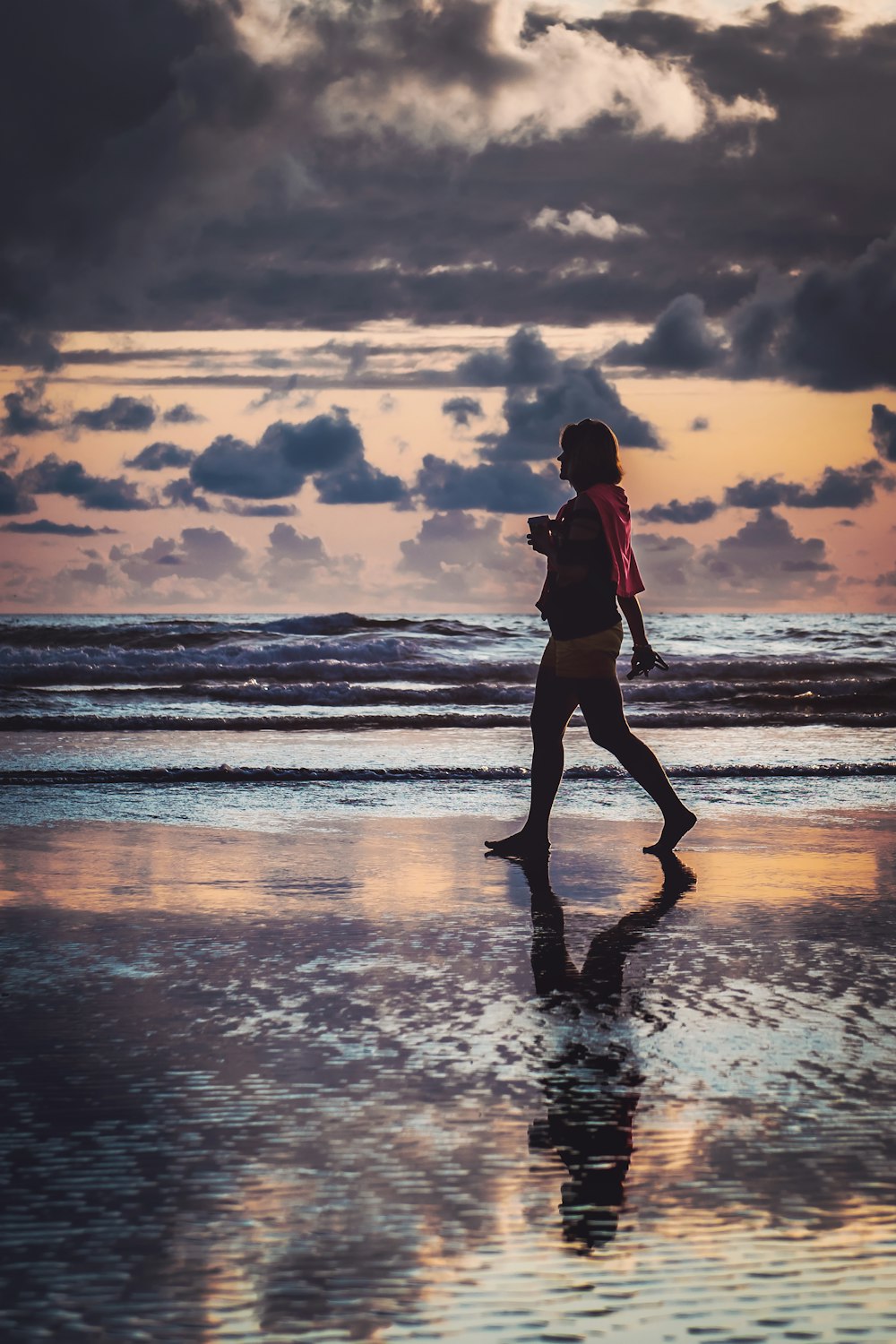 mulher que caminha na costa durante o dia