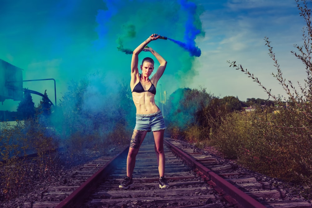 woman standing on a railway holding a smoke grenade
