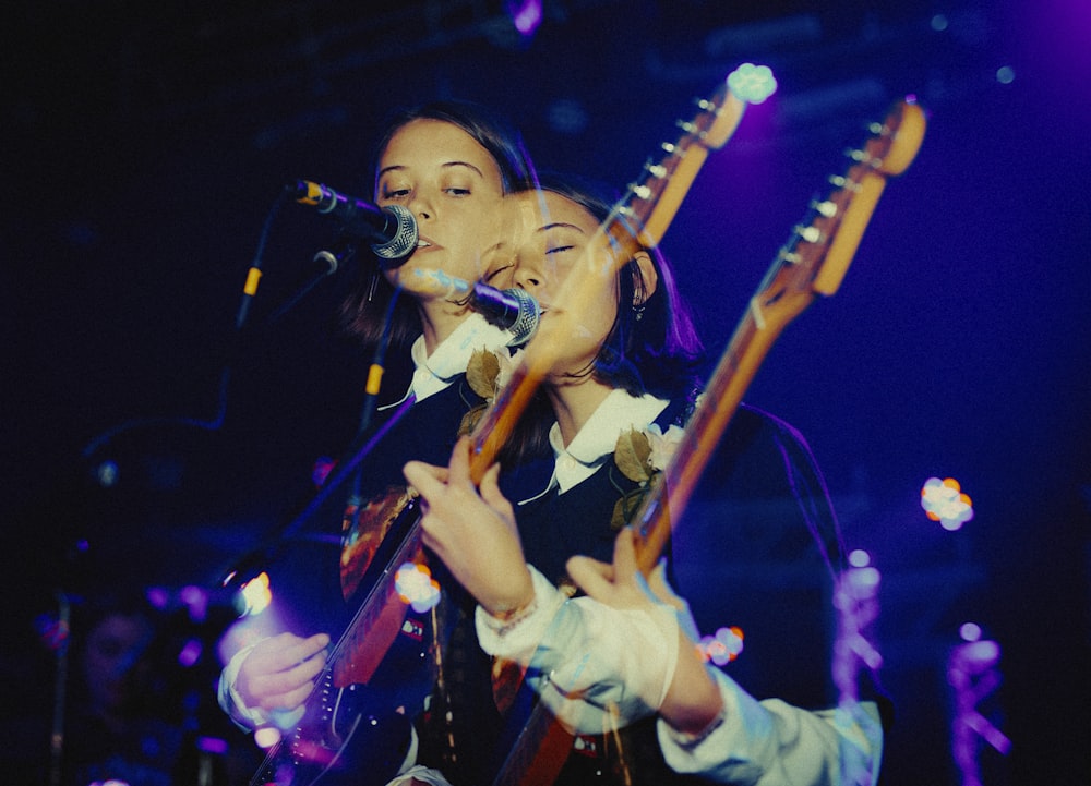 Frau spielt E-Gitarre beim Singen auf der Bühne