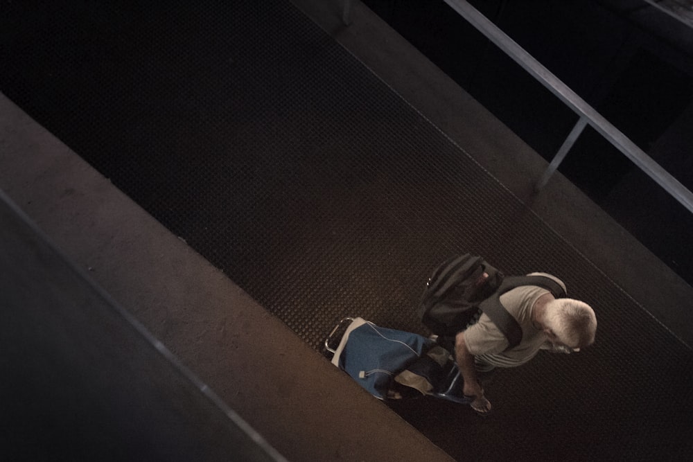 man pulling luggage while walking on hallway