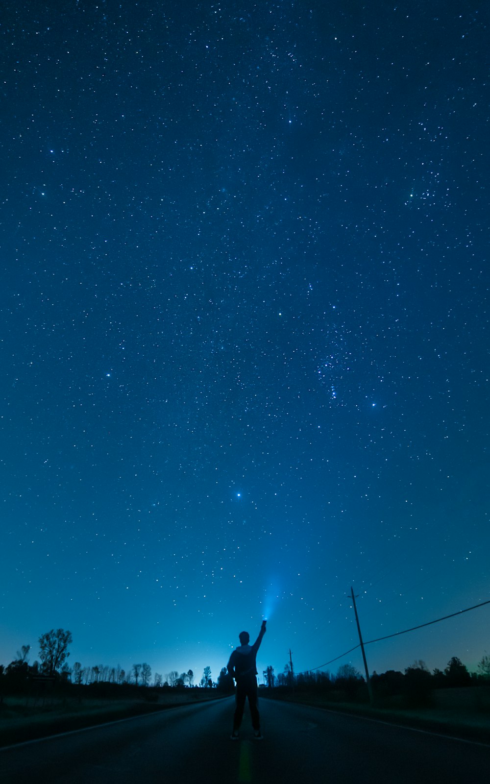 Un hombre parado al costado de una carretera bajo un cielo nocturno